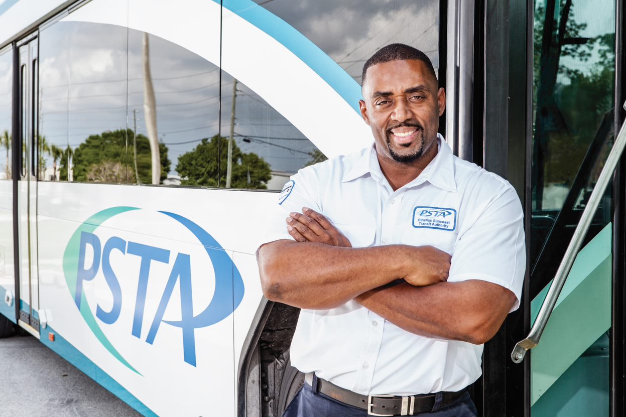 Operator standing outside bus door with his arms crossed