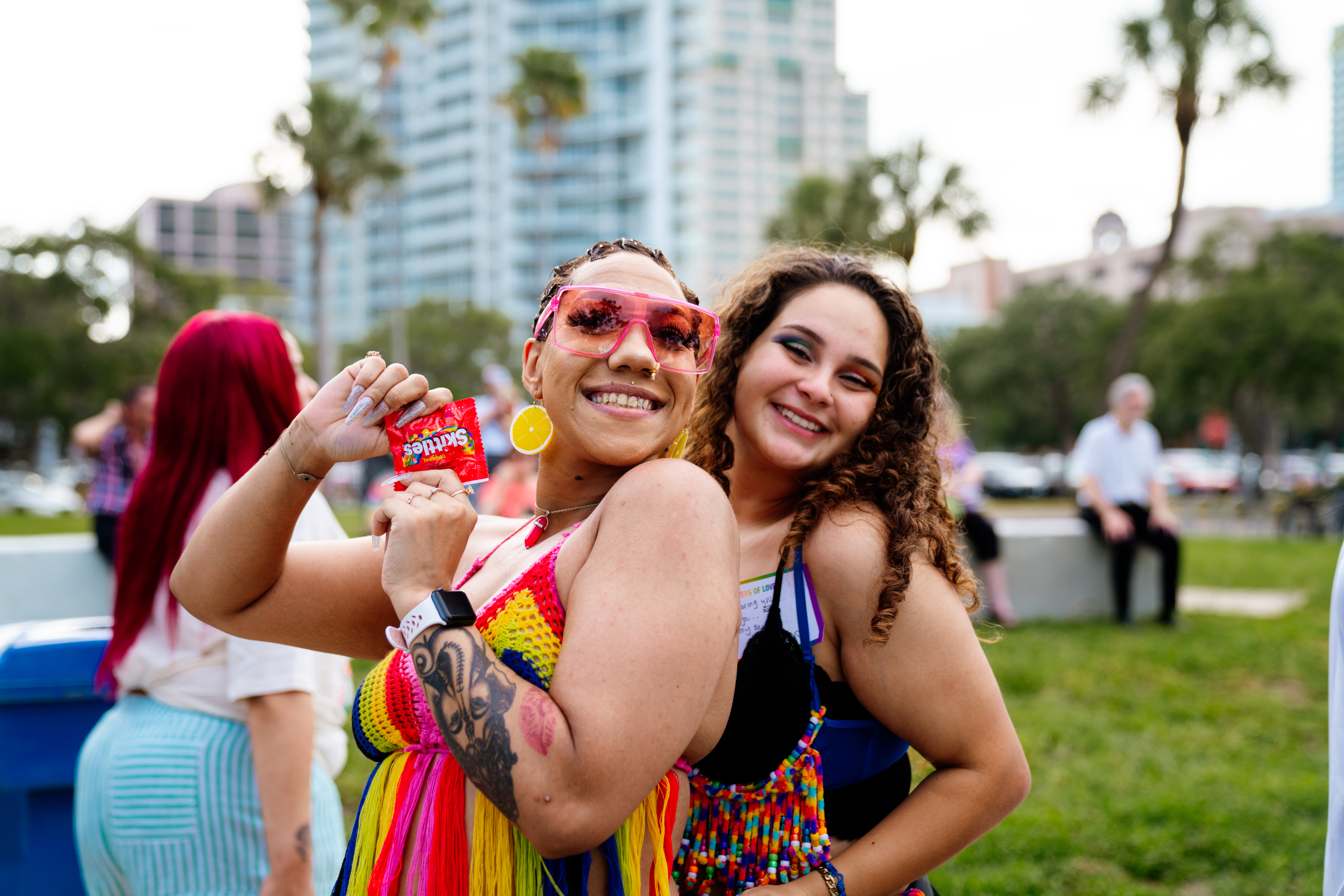 Two individuals smiling and holding Skittles bag