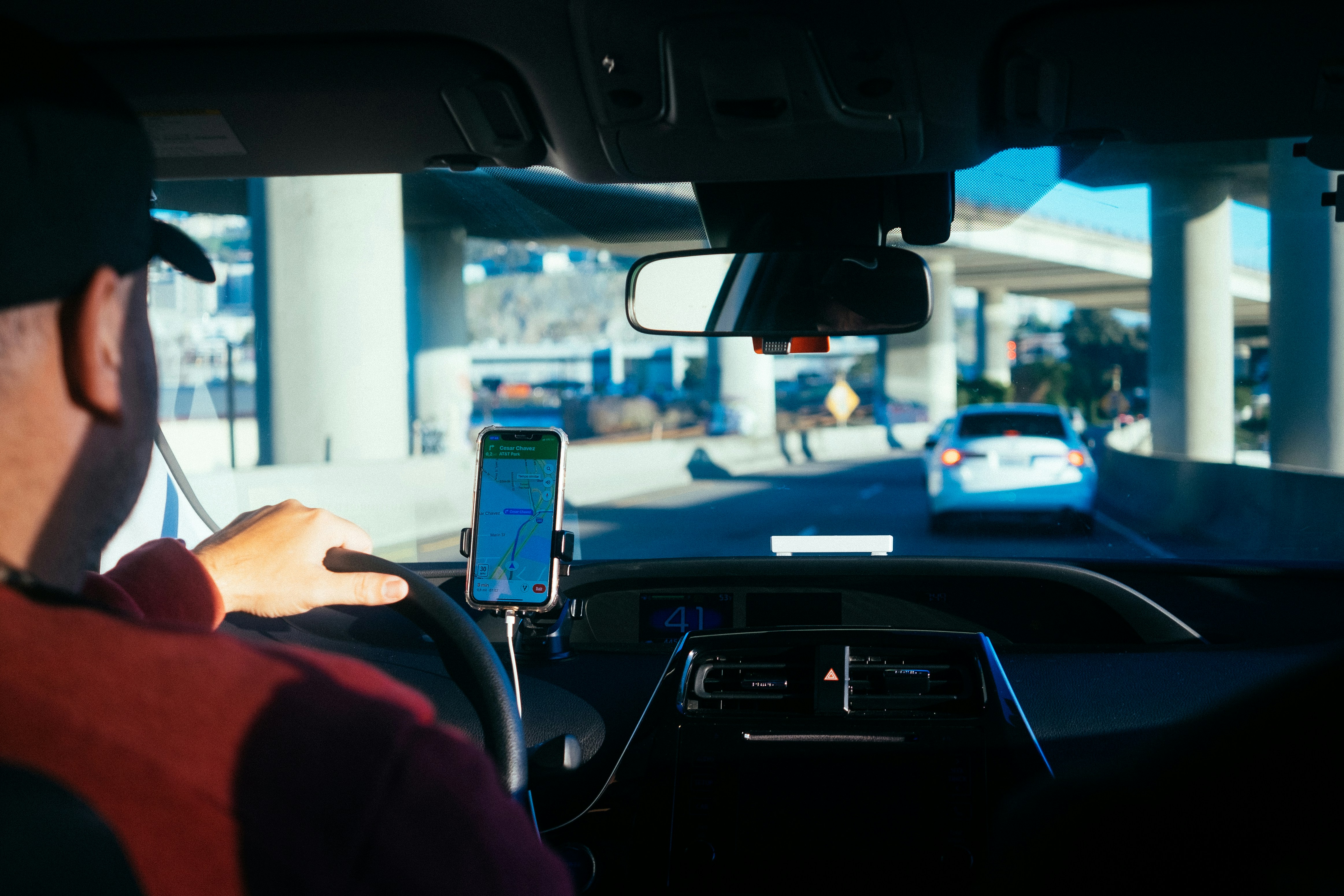 Photo taken over the shoulder of an Uber or Lyft driver driving under an overpass