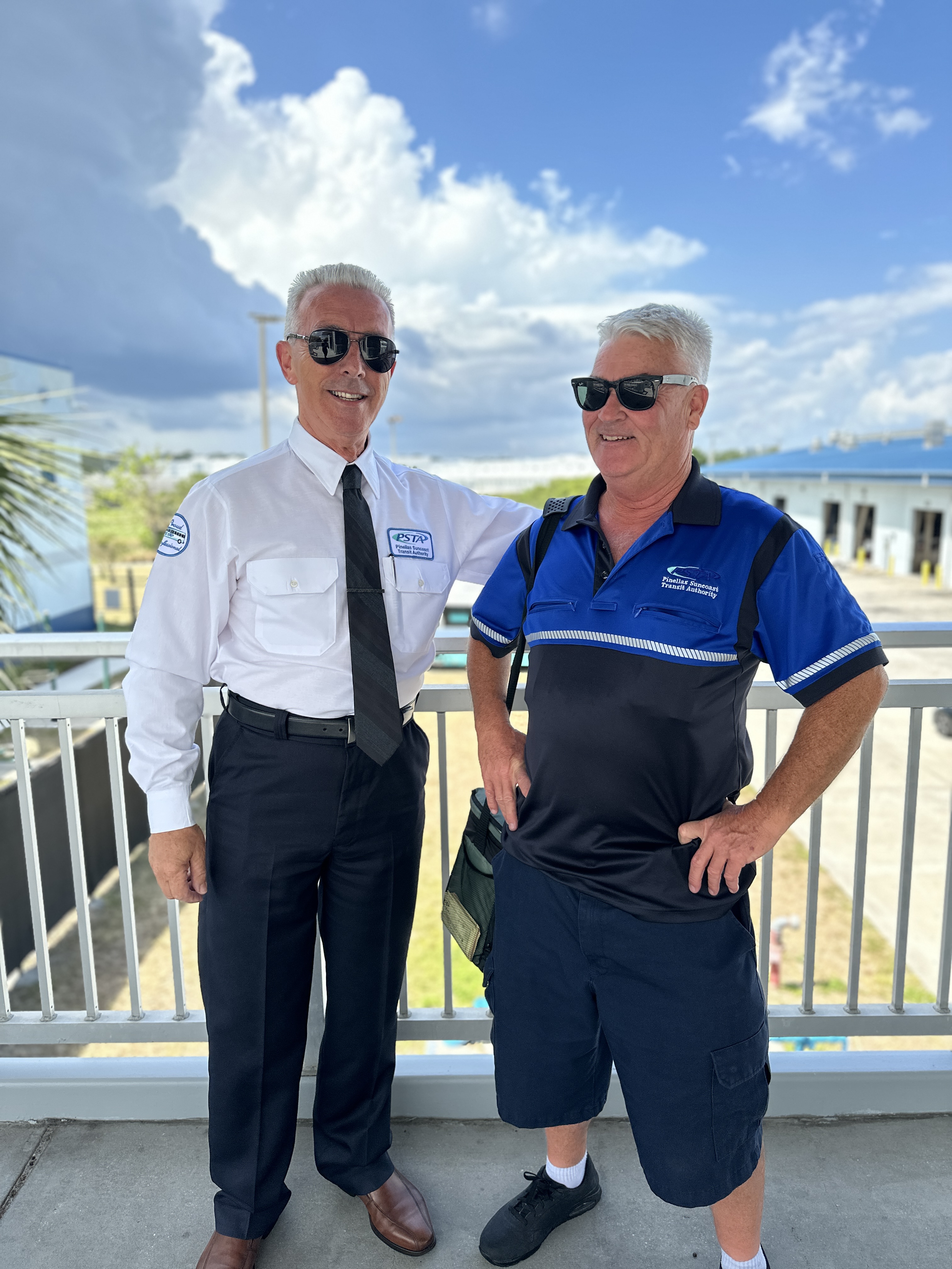 A photo of Milan standing alongside another bus operator wearing a blue and black PSTA shirt.